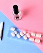 A box of press-on nails and nail glue on a blue and pink background