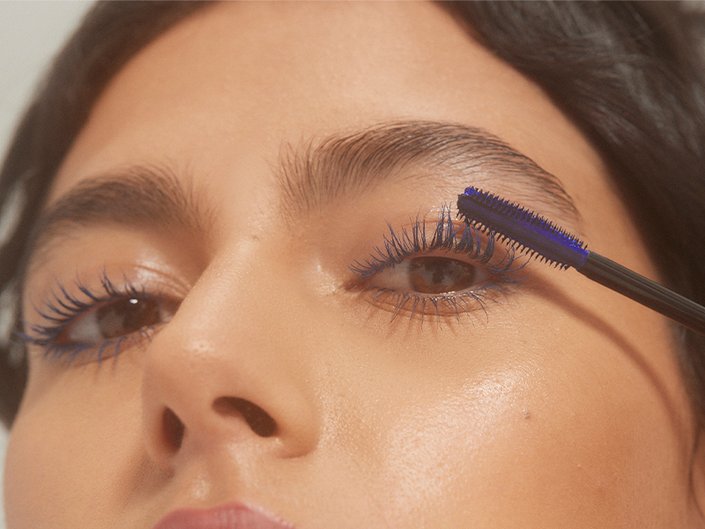 Close-up of a person applying blue mascara to their eyelashes