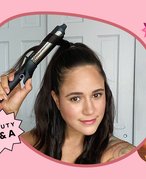 Woman curling her hair on pink graphic background