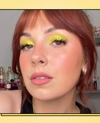 Picture of a person with hazel eyes and bright yellow eyeshadow on a graphic yellow background 