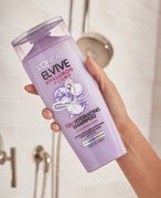 person holding loreal paris elvive shampoo with hyaluronic acid in the shower