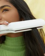 Person using a flat iron on their hair