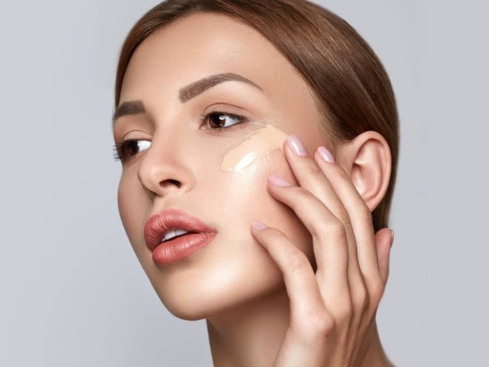 person applying foundation to cheekbone with finger