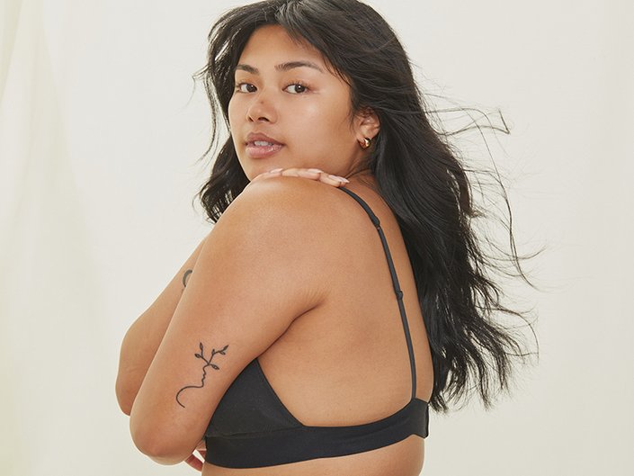 Picture of a model wearing a black bra, looking over their shoulder at the camera