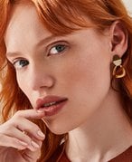 Person with red hair looking at the camera and touching their lips