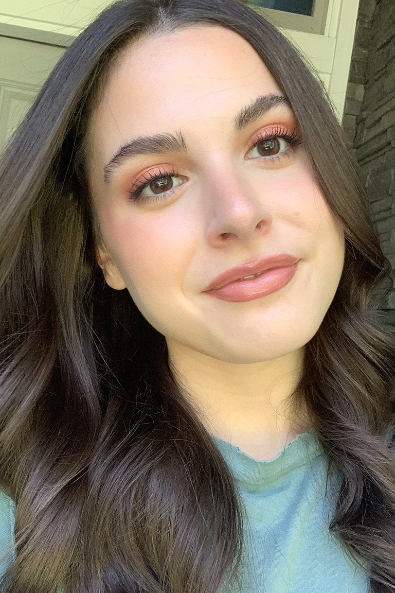 A woman with brown hair, natural foundation, and rose-colored lips and eyeshadow