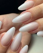 Close up of long, oval-shaped nails painted with milky neutral polish