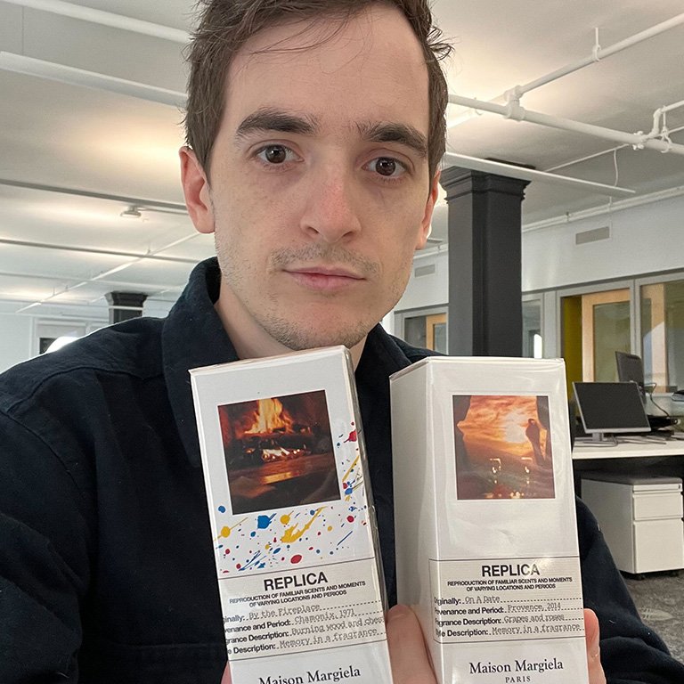 An image of the editor, Stephen Rubino, holding up two packaged bottles of Maison Margiela REPLICA fragrance.