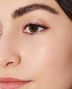 Close-up of a person’s face with long, dark hair, brown eyes and full eyebrows